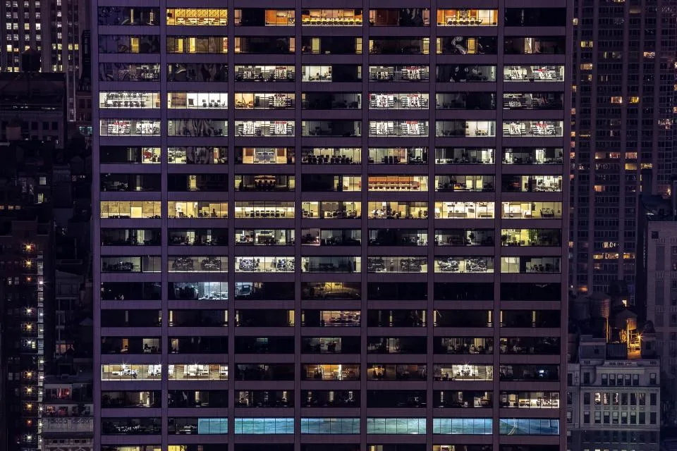 Office tower with many lit windows against a dark night sky