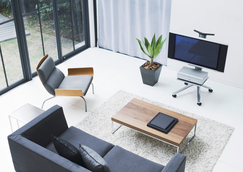 A bright living room with a sofa, armchair, coffee table and flat-screen TV