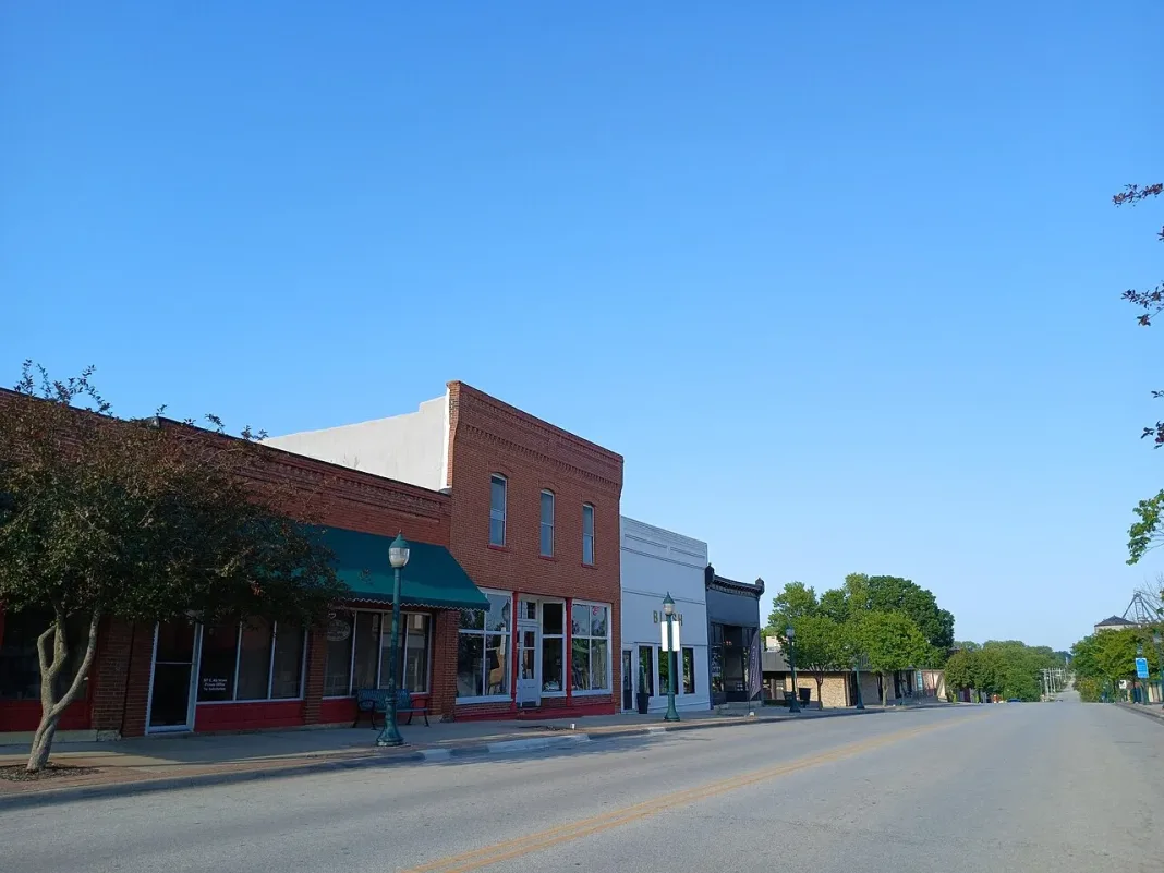 Brick storefronts along a quiet small-town main street under a blue sky