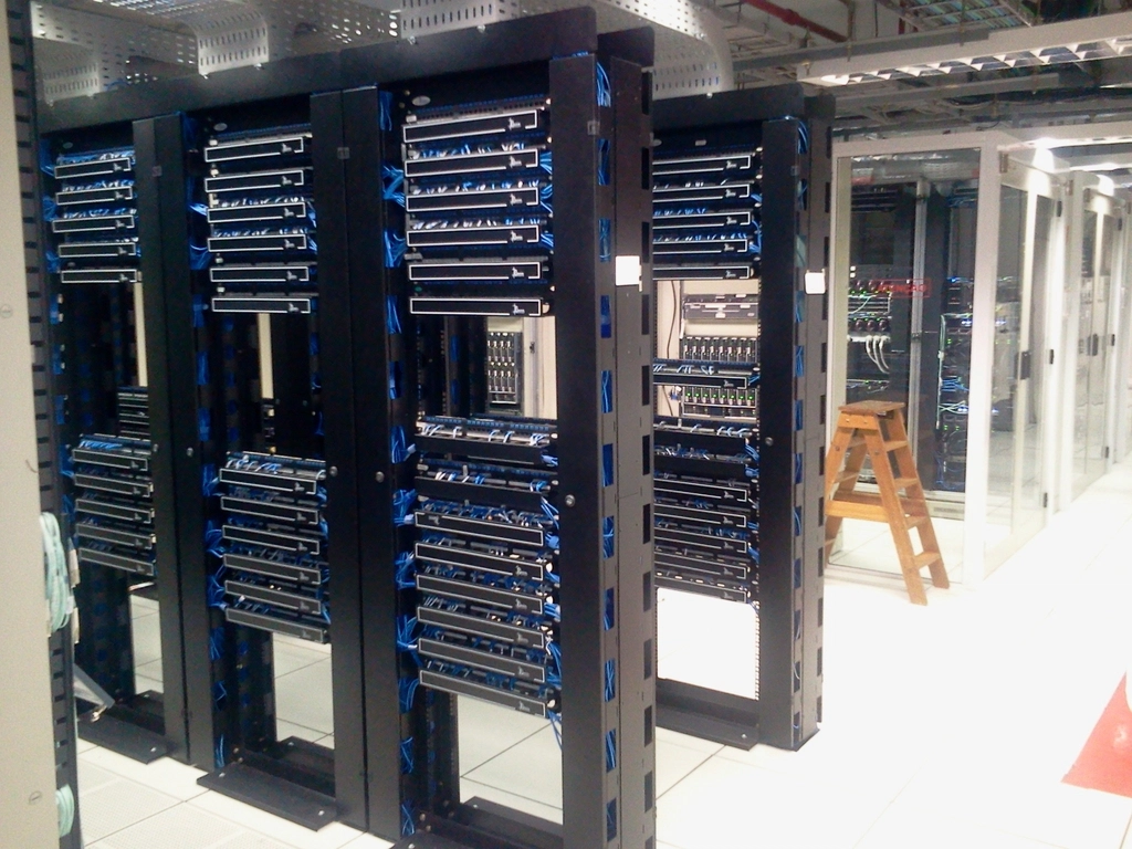 Rows of black server racks with blue network cables in a data center
