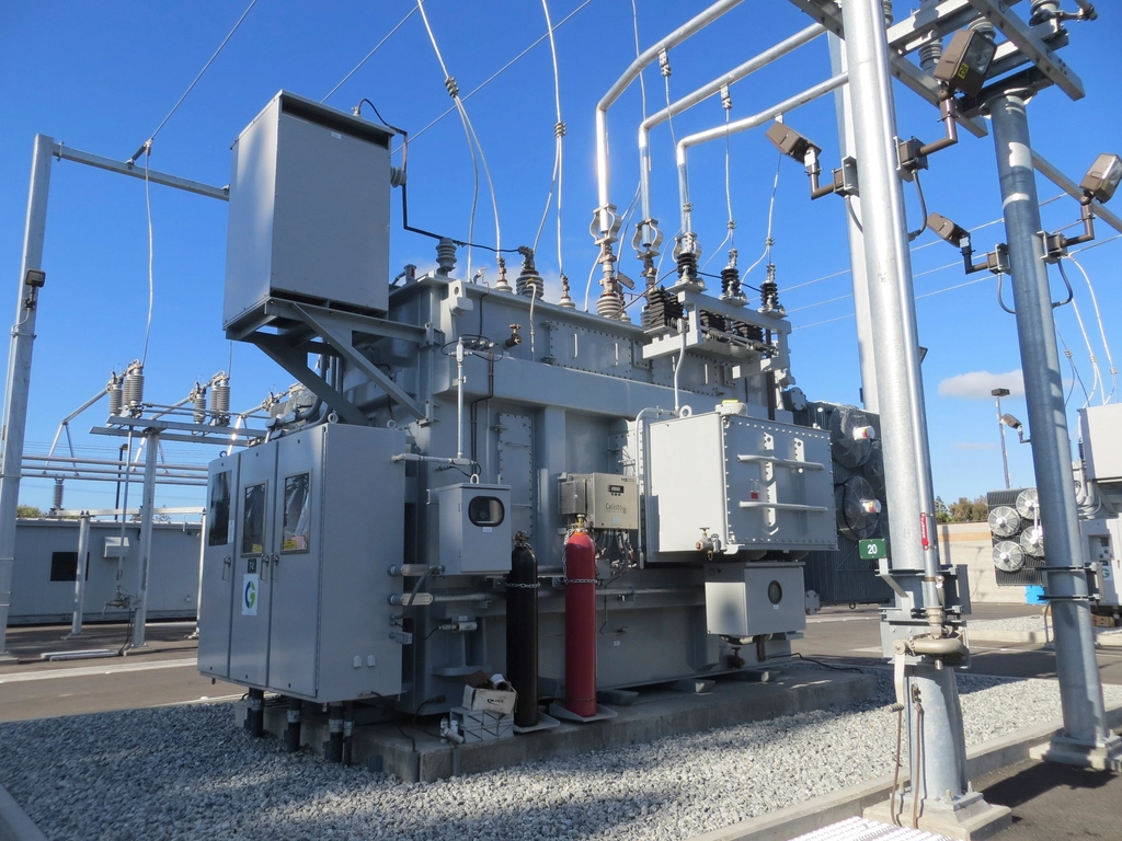 Transformers and equipment at an electrical substation under a blue sky