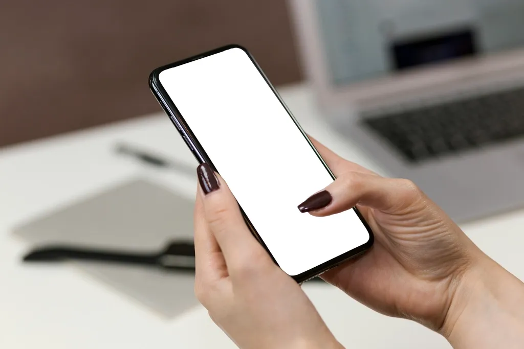Hands holding a smartphone with a blank screen