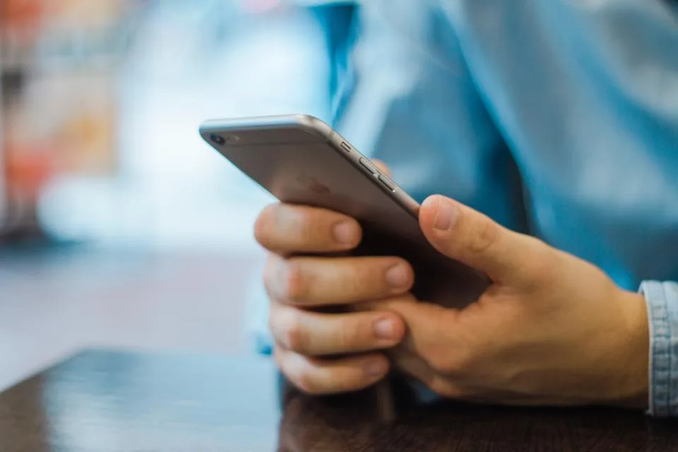 Close-up of hands holding a smartphone at a table