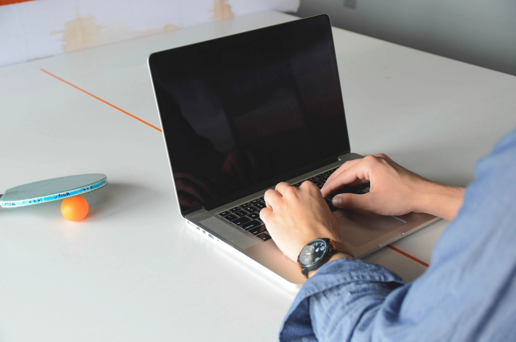 Hands typing on a laptop keyboard at a white table
