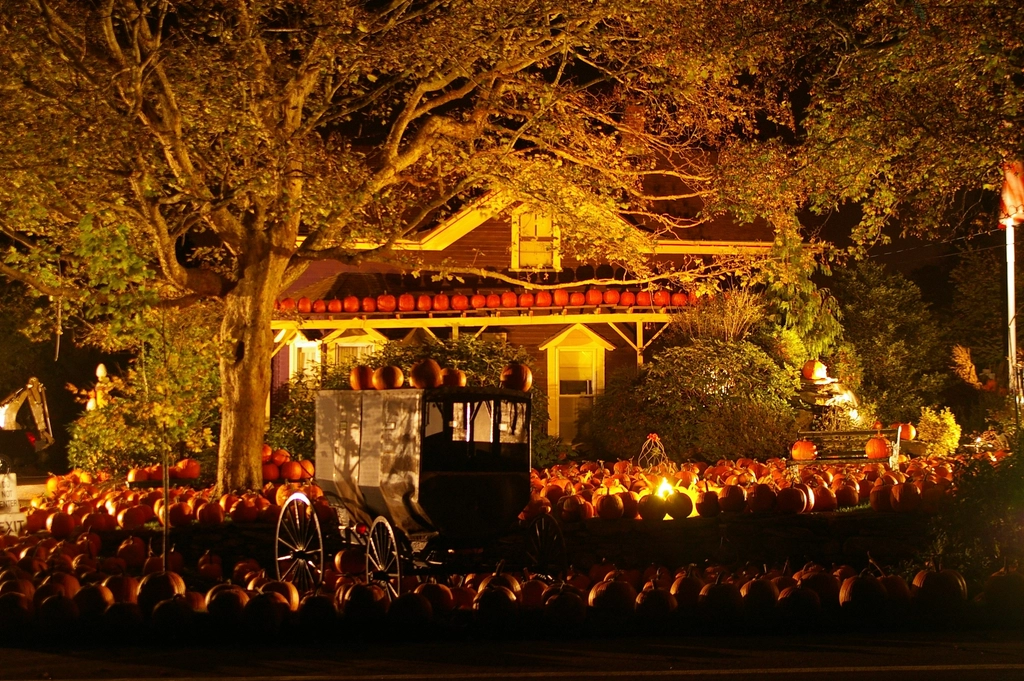 A house at night surrounded by hundreds of glowing pumpkins and jack-o’-lanterns