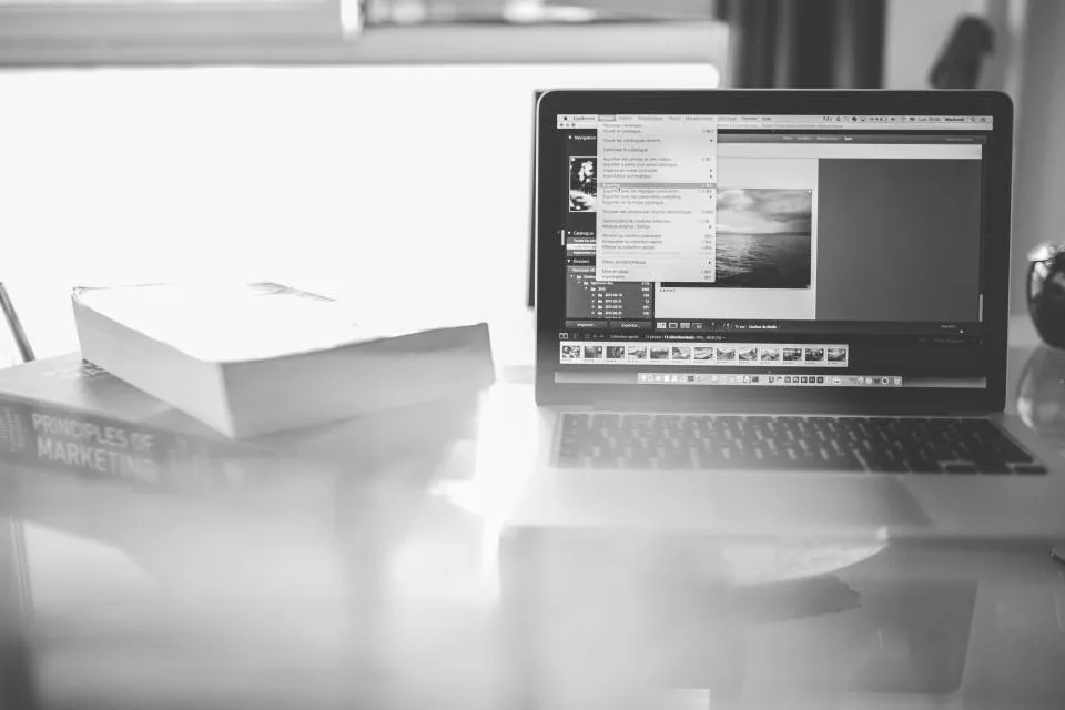 Laptop and marketing textbook on a desk in black and white