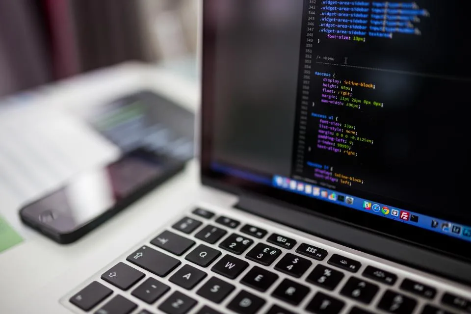 Laptop screen showing lines of code next to a smartphone