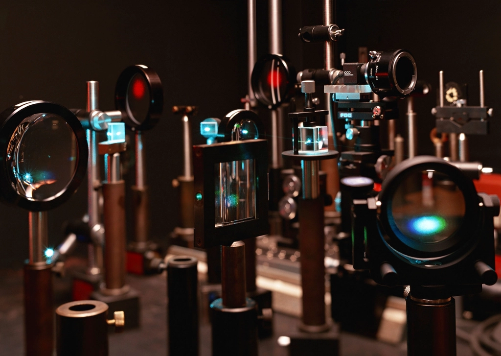 Laser optics and mirrors mounted on an optical table in a physics laboratory