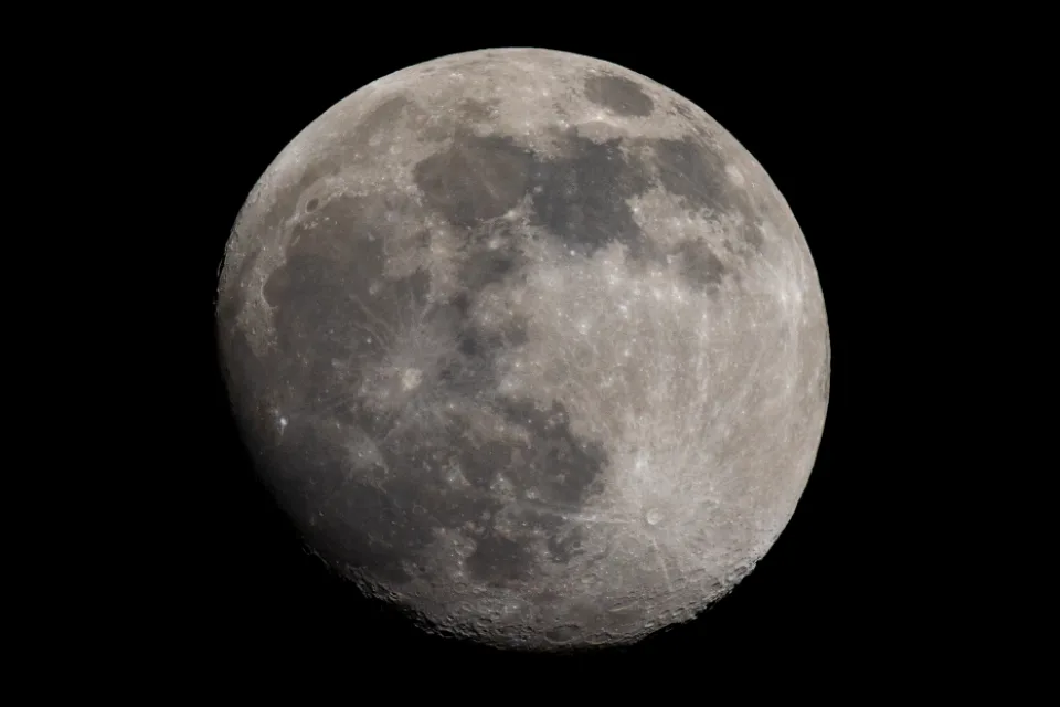 The near side of the Moon against a black sky, showing dark lava plains and bright cratered highlands