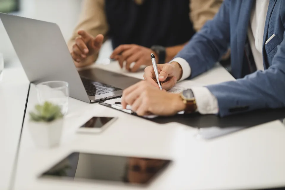 Colleagues working together at a table with a laptop, smartphone and paperwork