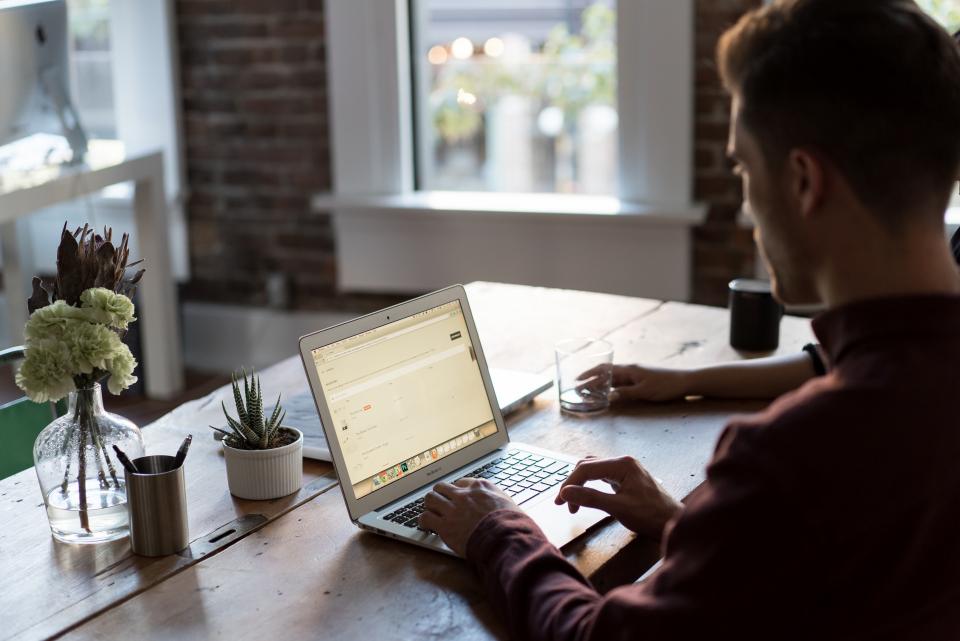 Person working on a laptop at a wooden desk