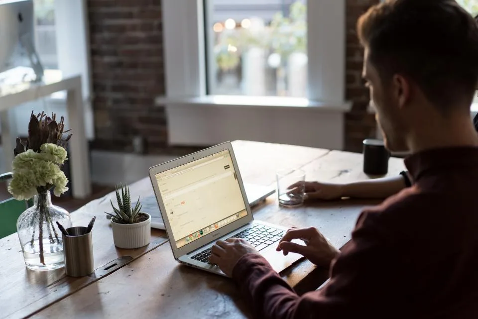 Person working on a laptop at a wooden desk