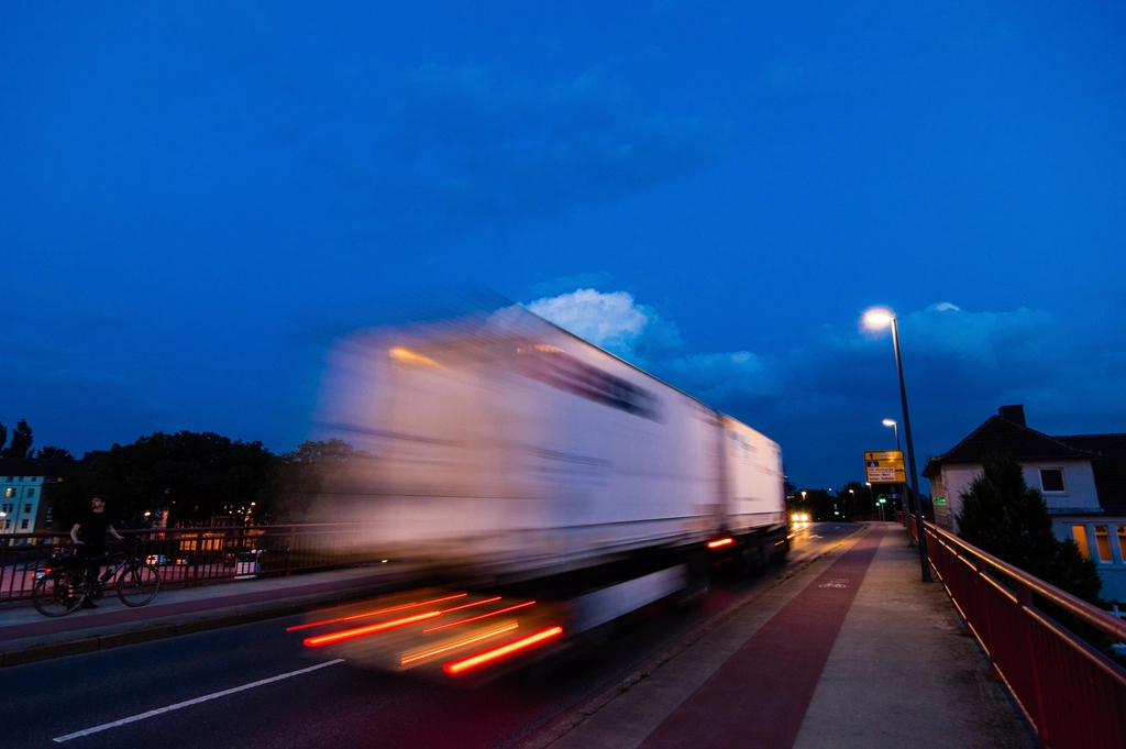 A truck speeding along a road at dusk, blurred by motion