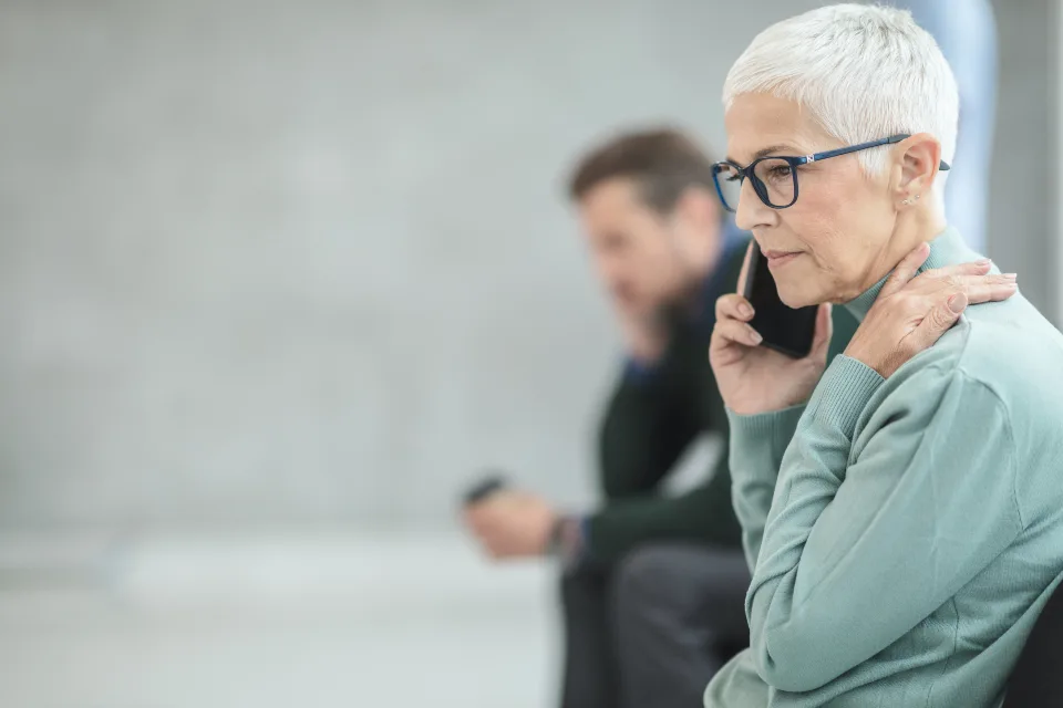 A woman waits on a phone call while sitting in a waiting area